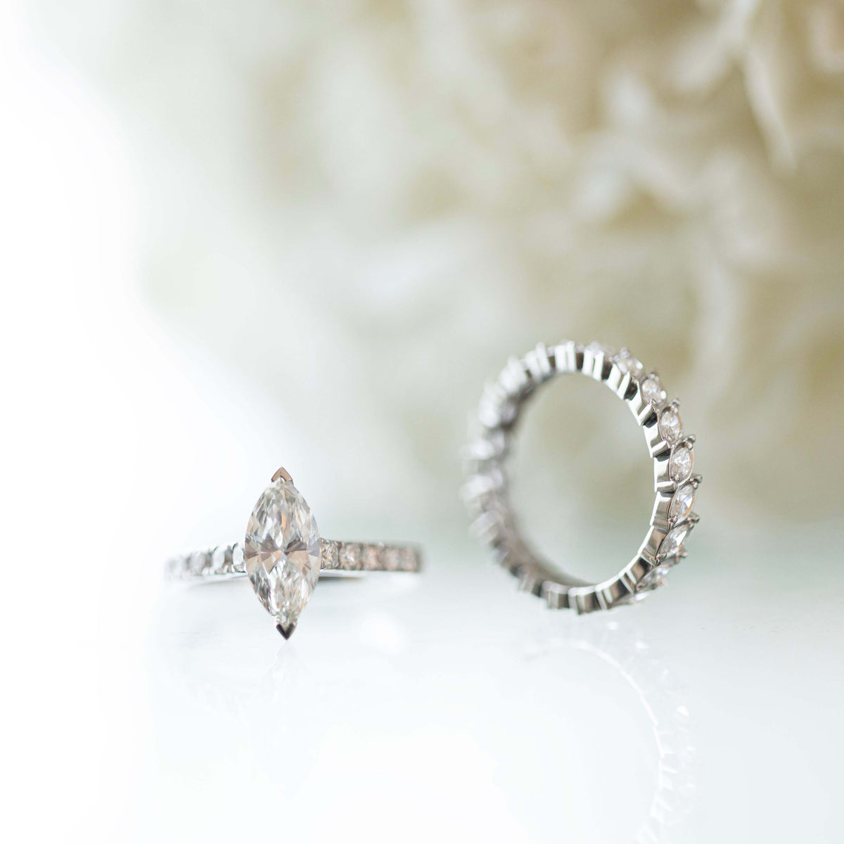 خاتم الخطوبة Marquise Promise من الذهب الأبيض بماسة ماركيز طبيعية وزنها 1 قيراط، بجانب دبلة Eternal Marquise المرصّعة بألماس الماركيز