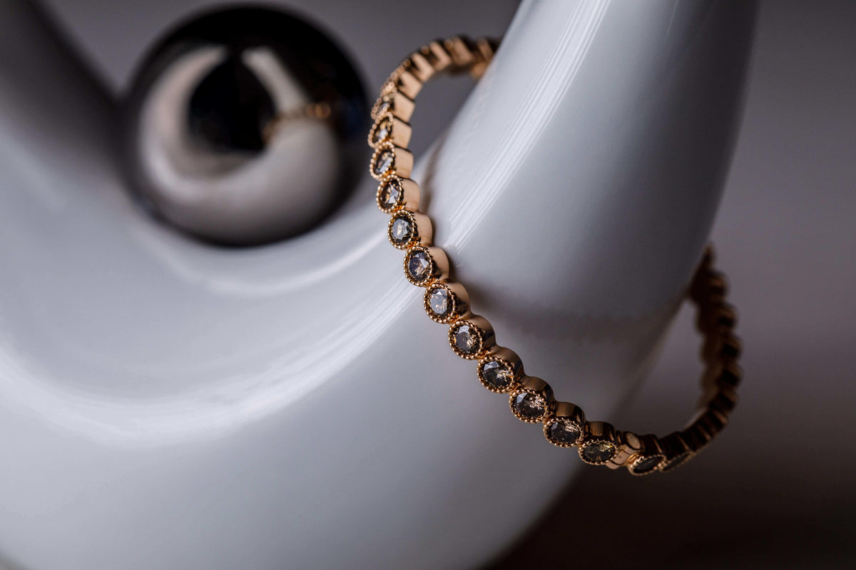 A gold and gemstone bracelet laid on a stone surface in the Caleums atelier