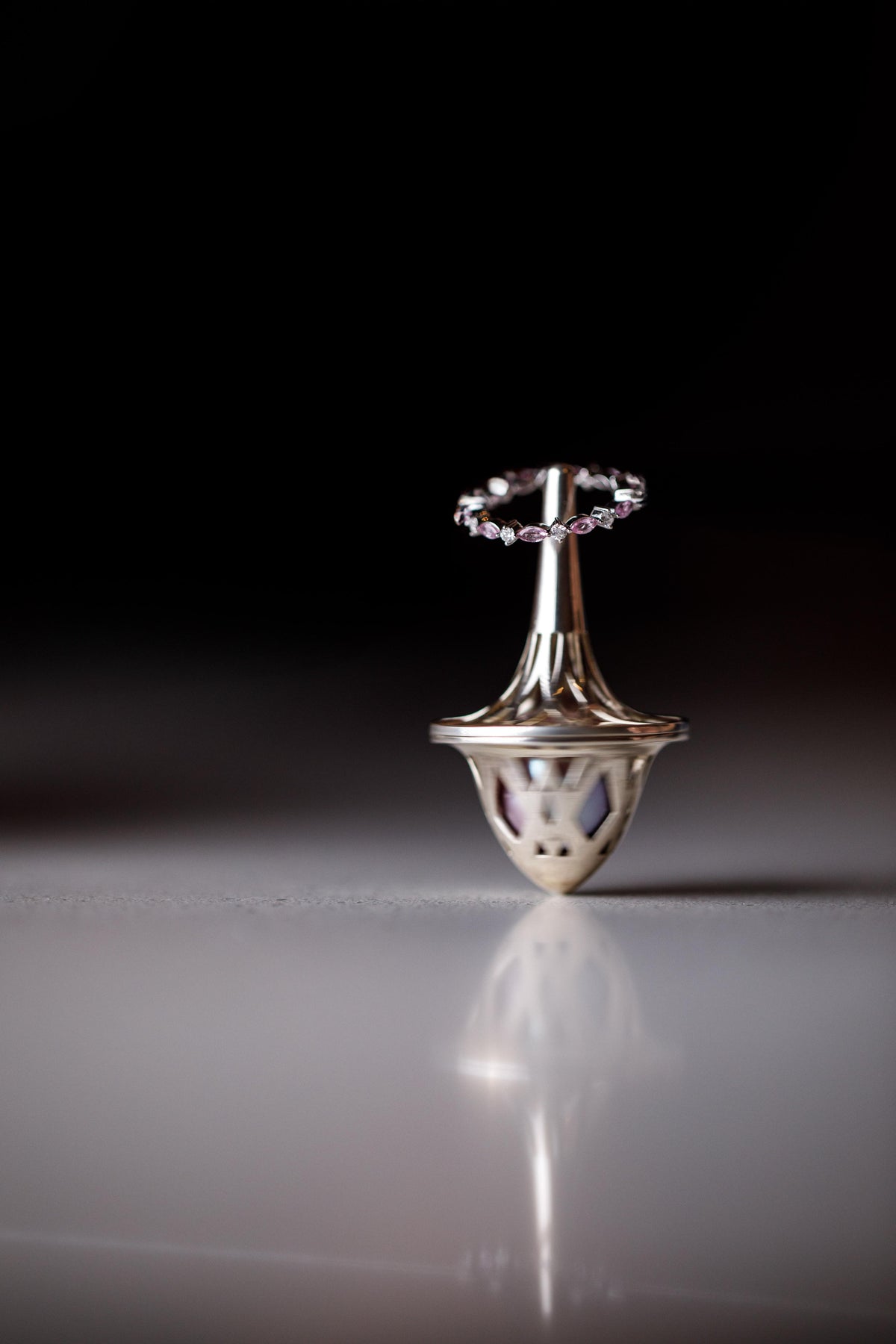 A silver spinning top on a reflective surface